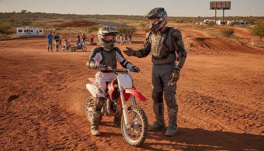Instructor guiding a first-time dirt bike rider at an outdoor motocross facility